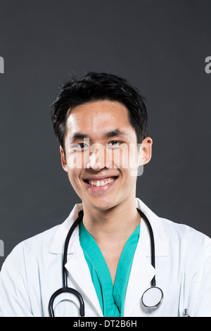 Porträt eines männlichen asiatischen Arzt tragen grün Scrubs. Dunkel grau hinterlegt. Stockfoto