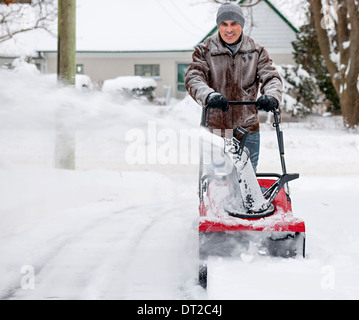 Mann mit Schneefräse, Tiefschnee auf Wohn Einfahrt nach starkem Schneefall zu löschen Stockfoto