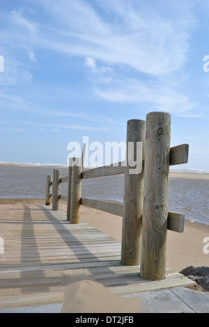 Eine Holzterrasse mit Holzgeländer am Strand mit blauem Meer und Himmel in Gruissan Plage. Stockfoto