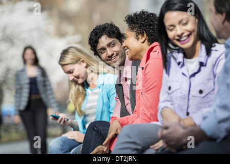 Fünf Leute sitzen in einer Reihe im park Stockfoto