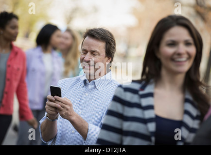 Menschen im Freien in der Stadt im Frühjahr mal ein Mann sein Handy unter Kontrolle Stockfoto