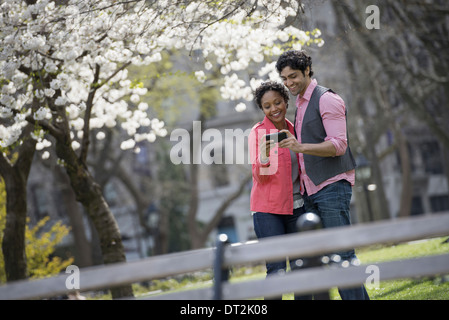 New York City Park A Mann und Frau nebeneinander mit dem Fotografieren mit einer Hand statt Handy Stockfoto