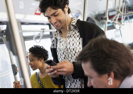 New York City Park Menschen Männer und Frauen auf einem Stadtbus ÖPNV in Kontakt zu bleiben, einen jungen Mann sein Handy prüfen Stockfoto