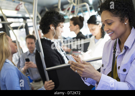 New York City Männer und Frauen Bus ÖPNV in Kontakt zu bleiben, eine junge Frau überprüfen oder über ihr Handy Stockfoto