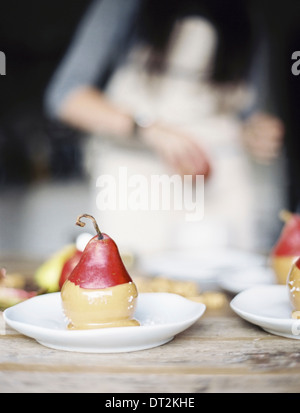 Eine Frau in einer Küche frische Bio Birnen tauchte in einer Sauce zum Nachtisch auf Platten gelegt Stockfoto