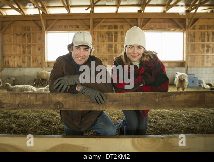 Ein Bio-Bauernhof im Winter im kalten Frühling New York Zustand ein Bauer und eine Frau, die von einem Stift voller Schafe Stockfoto