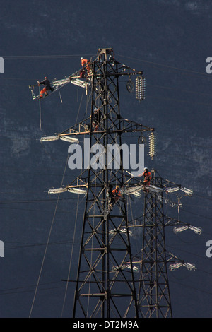 Arbeiter an Strommasten in Italien. Wartungsarbeiten von einer Hochspannungs-Leitung. Stockfoto