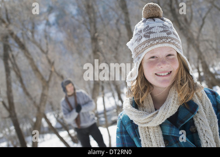 Winterlandschaft mit Schnee auf dem Boden A junge Mädchen mit einem Bommel Mütze und Schal im freien A Mann im Hintergrund Stockfoto