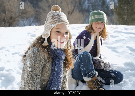 Winterlandschaft mit Schnee auf dem Boden A Frau und ein Kind sitzen auf dem Boden vor Lachen Stockfoto