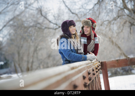 Winterlandschaft mit Schnee auf den Boden A paar junger Mann und junge Frau, die an einen Zaun gelehnt Stockfoto