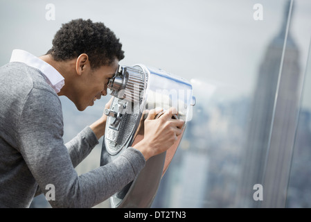 Blick über Stadt junger Mann, Blick über die Stadt durch ein Teleskop Stockfoto