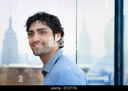 Urban Lifestyle A junger Mann mit schwarzen lockigen Haaren trug ein blaues Hemd in der Lobby eines Gebäudes Stockfoto