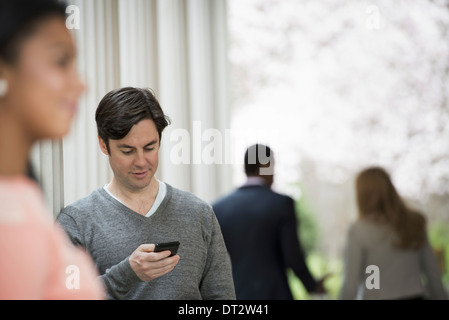 Junge Menschen Frühling Männer und Frauen zwei Personen eine Überprüfung sein Telefon wieder Blick auf zwei Personen im park Stockfoto