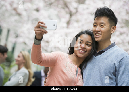 Blick über CityYoung Menschen im Freien in einem Stadtpark A paar unter einem Selbstporträt oder selfy mit einem Smartphone Stockfoto