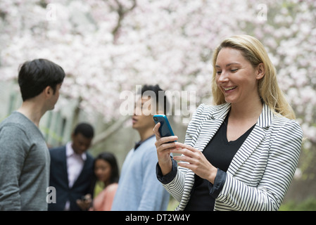 Blick über CityA Frau mit ihrem Handy und eine Gruppe von vier Personen-Männer und Frauen im Hintergrund Stockfoto