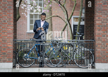 Blick über CityYoung Menschen in einer Stadt Park A Mann in einem Anzug neben einem Fahrradpark auf einem Bürgersteig mit seinem Smartphone