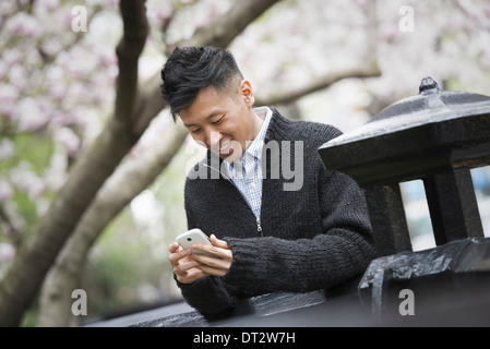 Blick über CityA junger Mann im Freien in einer Stadt park auf einer Bank sitzend Stockfoto