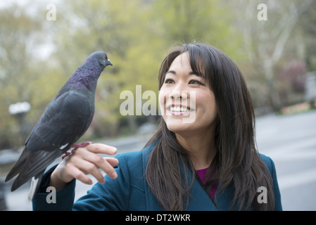 Eine junge Frau mit einer Taube im Park thront an ihrem Handgelenk Stockfoto