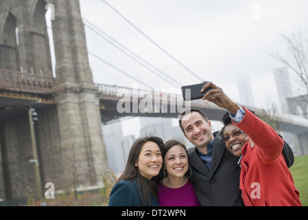New York City The Brooklyn Bridge Crossing über den East River vier Freunde, die Aufnahme eines Bildes mit einem Telefon eine selfy von sich selbst Stockfoto