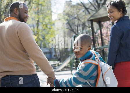 Sonnenschein und Cherry blossom ein Junge über seine Schulter zwischen seinen Eltern Stockfoto