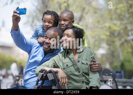 Eine Familie Eltern und zwei jungen, die mit dem Fotografieren mit einem Smartphone Stockfoto