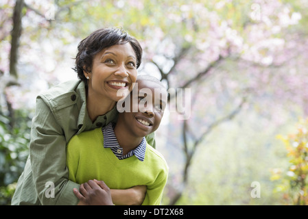 Sonnenschein und Kirschen blühen, Mutter und Sohn umarmen und lachen Stockfoto
