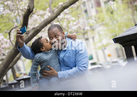New York City Frühlingssonne und Kirschblüte A Vater und Sohn Seite an Seite mit einem Smartphone zu fotografieren Stockfoto