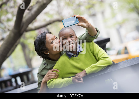 New York City Park im Frühling Sonnenschein und Cherry blossom eine Frau, die ein Bild von sich und ihren Sohn mit einem Smartphone Stockfoto