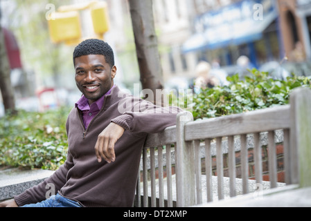 Ein junger Mann sitzt auf einer Bank Stockfoto