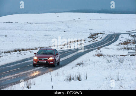 Mynydd Epynt, Powys, Wales, UK. 7. Februar 2014. Fahrzeuge die verschneite Straße zwischen Builth Wells und Brecon unter ominösen Himmel zu verhandeln. Schnee fiel gestern Abend auf dem hohen Gelände Mid-Wales. Bildnachweis: Graham M. Lawrence/Alamy Live-Nachrichten. Stockfoto