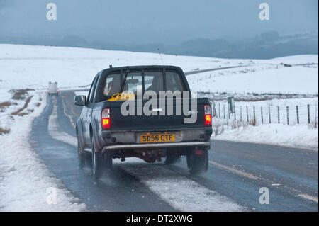 Mynydd Epynt, Powys, Wales, UK. 7. Februar 2014. Fahrzeuge die verschneite Straße zwischen Builth Wells und Brecon unter ominösen Himmel zu verhandeln. Schnee fiel gestern Abend auf dem hohen Gelände Mid-Wales. Bildnachweis: Graham M. Lawrence/Alamy Live-Nachrichten. Stockfoto