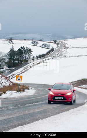 Mynydd Epynt, Powys, Wales, UK. 7. Februar 2014. Fahrzeuge die verschneite Straße zwischen Builth Wells und Brecon unter ominösen Himmel zu verhandeln. Schnee fiel gestern Abend auf dem hohen Gelände Mid-Wales. Bildnachweis: Graham M. Lawrence/Alamy Live-Nachrichten. Stockfoto