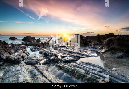 Ozean Sonnenaufgang an einem steinigen Strand in Looe in Süd Cornwall Stockfoto