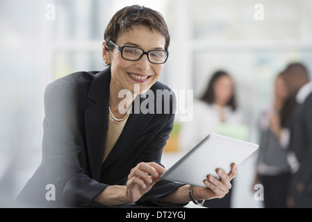 Ein Büro innen A Frau in eine schwarze Jacke mit einem digitalen tablet Stockfoto