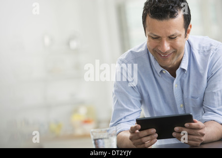 Ein Mann in ein blaues Hemd, stützte sich auf einen Schreibtisch mit einem digital-Tablette Stockfoto