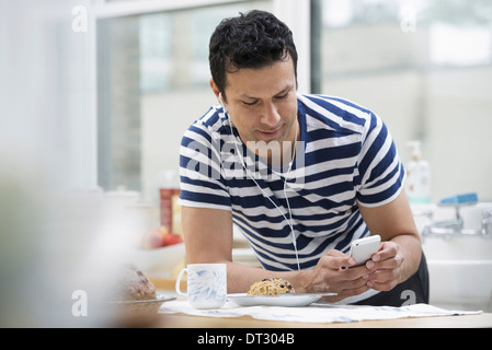 Ein Büro oder Wohnung innen in New York City A Mann in einem gestreiften t-Shirt stützte sich auf die Frühstücks-Bar Stockfoto