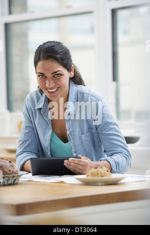 Ein Büro oder eine Wohnung in New York City A junge Frau in ein Jeanshemd mit einem digitalen Tablet innen Stockfoto