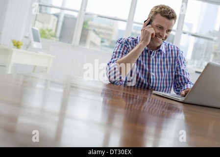 Ein Mann telefonieren und tippen auf seinem laptop Stockfoto