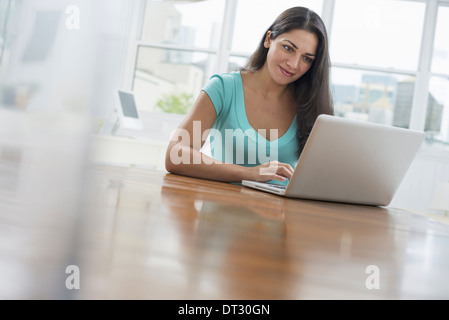 Eine junge Frau sitzt bequem in einer ruhigen luftig Büroumgebung Stockfoto
