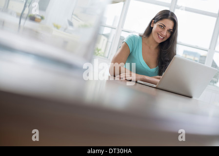 Eine junge Frau sitzt bequem in einer ruhigen luftig Büroumgebung mit einem laptop Stockfoto