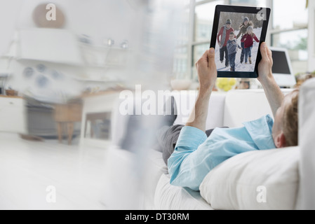 Ein Mann liegt auf dem Sofa bequem und in einer ruhigen luftig Büroumgebung mit einem digitalen tablet Stockfoto
