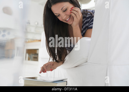 Geschäftsleute die Büro Sommer A Frau liegend auf den Bauch auf dem Sofa in ruhigen luftig Büroumgebung mit einem Smartphone Stockfoto