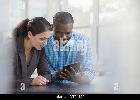 Profis im Büro ein hellen und luftiger Ort der arbeiten zwei Personen sitzen an einem Schreibtisch mit einem digitalen tablet Arbeitskollegen Stockfoto