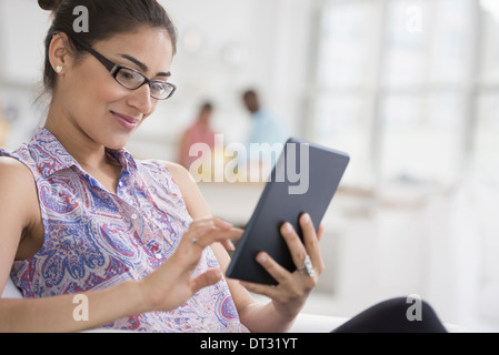 Profis in der Büro-A-Licht und luftig Ort der Arbeit eine junge Frau sitzend mit einem digitalen tablet Stockfoto