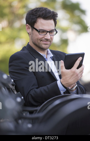 Ein Mann sitzt auf einer Bank mit einem digitalen tablet Stockfoto