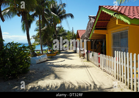 Sandigen Pfad entlang des Meeres mit Schatten der Kokospalmen und Urlaub Bungalows, Carenero Karibikinsel, Panama Stockfoto