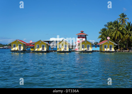 Tropischen Urlaub Bungalows über dem Wasser mit Kokospalmen am karibischen Meer, Bocas del Toro, Panama Carenero Insel Stockfoto