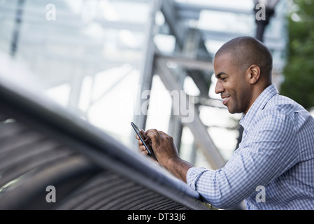 Ein Mann in Hemdsärmeln Überprüfung seiner Smartphone Stockfoto