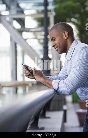 Ein Mann in Hemdsärmeln Überprüfung seiner Smartphone Stockfoto