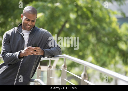 Ein Mann in ein Sweatshirt Blick auf seinem Smartphone Stockfoto